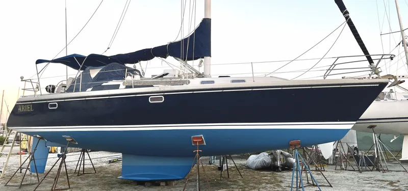 Slide: The Image of 1992 Catalina 42 MK 1 sailboat on stands, dark blue hull, white deck, in a boatyard. - 14