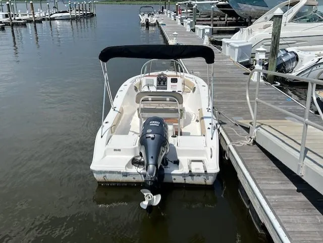 Slide: The Image of 2016 Sea Fox 186 Commander boat docked at marina, featuring outboard motor and canopy. - 2