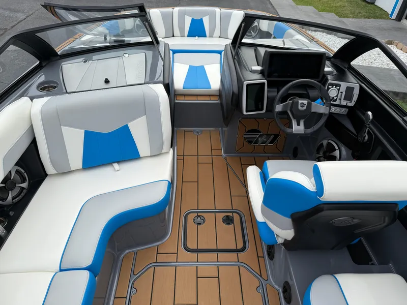 Slide: The Image of 2020 Malibu Wakesetter 23 MXZ interior with blue and white seating, modern dashboard, and wood-style flooring. - 15
