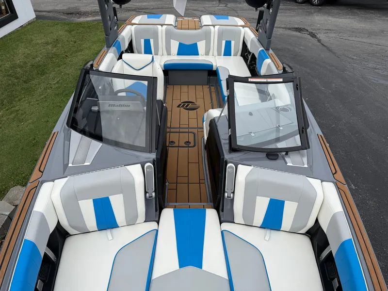 Slide: The Image of 2020 Malibu Wakesetter 23 MXZ interior with blue and white seating, open windshield, and teak flooring. - 18