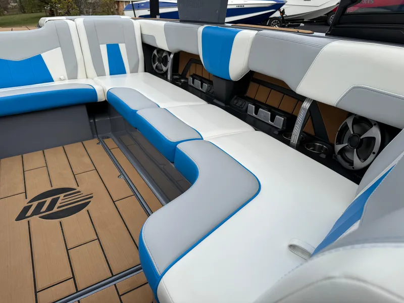 Slide: The Image of 2020 Malibu Wakesetter 23 MXZ interior with blue and white seating, teak flooring, and speakers. - 20