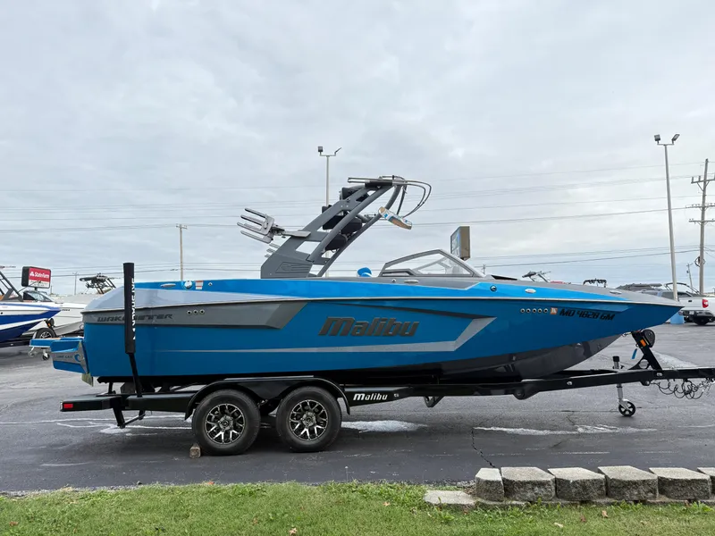 Slide: The Image of 2020 Malibu Wakesetter 23 MXZ boat in blue, parked on a trailer in a lot. - 4