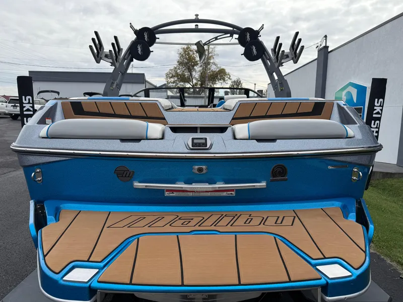 Slide: The Image of 2020 Malibu Wakesetter 23 MXZ boat, blue exterior, teak deck, rear view, parked outdoors. - 7