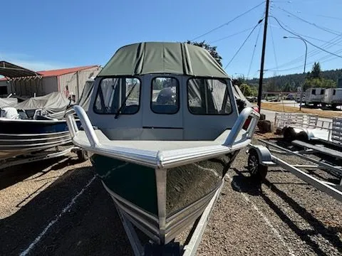 Slide: The Image of 2019 Klamath 19 GTX boat with green canopy on trailer, parked outdoors. - 3