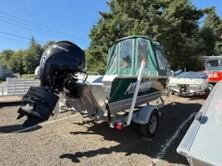 Slide: The Image of 2019 Klamath 19 GTX boat on trailer, parked outdoors, with green canopy and outboard motor. - 4