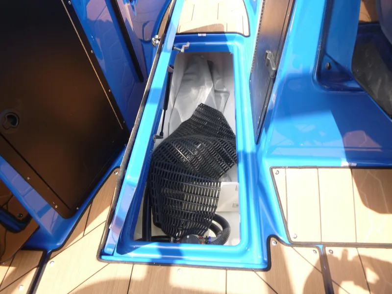 Slide: The Image of Storage compartment of 2025 Yamaha Boats 222XD, featuring blue interior and black accessories. - 12