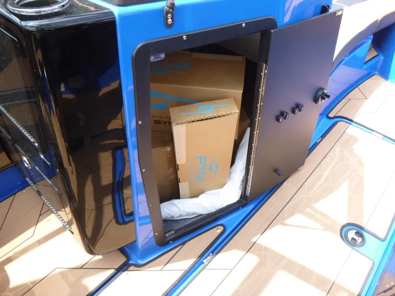 Slide: The Image of Open storage compartment on 2025 Yamaha Boats 222XD, revealing cardboard boxes inside. - 13