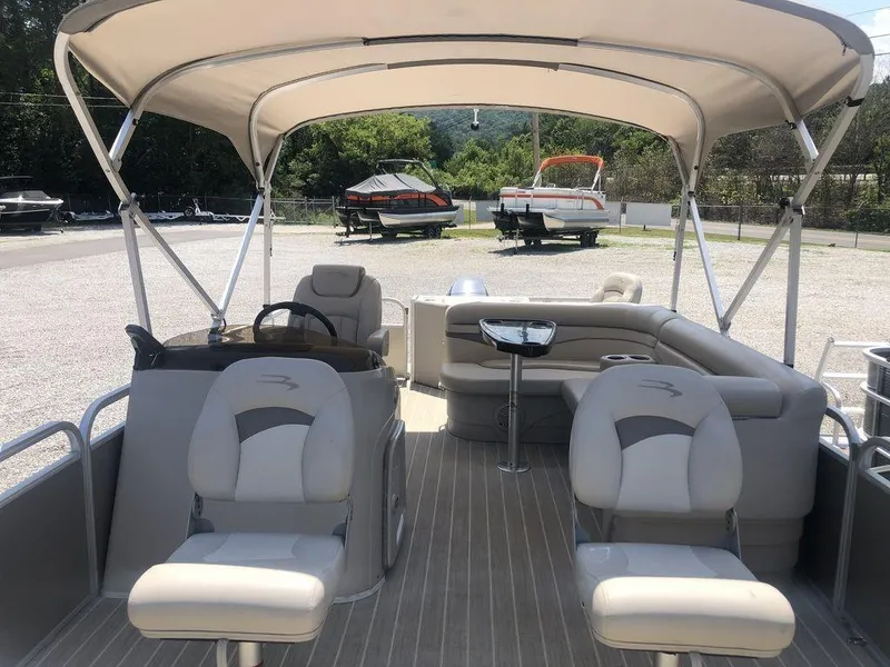Slide: The Image of 2024 Bennington 20 SF pontoon boat with canopy and seating, parked outdoors. - 3