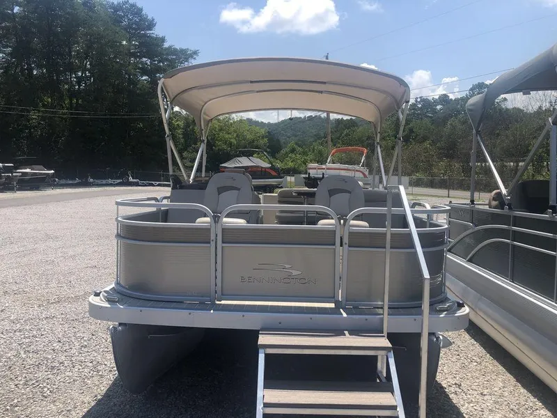 Slide: The Image of 2024 Bennington 20 SF pontoon boat with canopy, parked outdoors on gravel. - 4