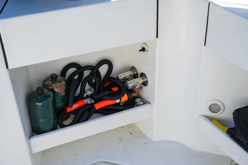 Slide: The Image of Storage compartment in a 2021 Ocean Sport 26/27 boat with hoses and gas canisters. - 14