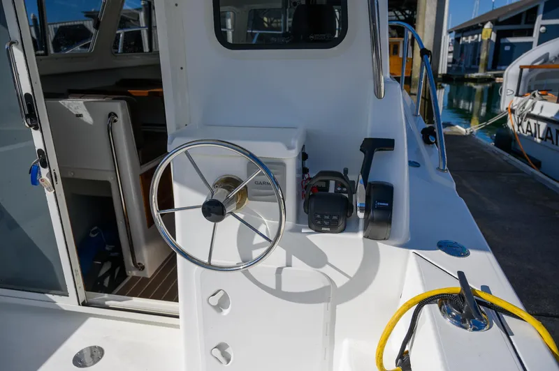 Slide: The Image of 2021 Ocean Sport 26/27 boat helm with steering wheel and controls, docked at marina. - 16