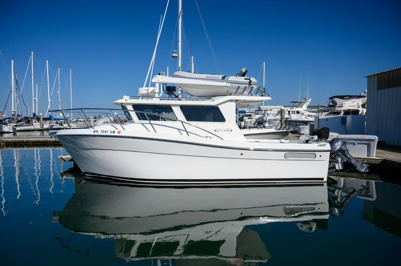 Slide: The Image of 2021 Ocean Sport 26/27 boat docked in marina, clear blue sky, calm water reflection. - 4