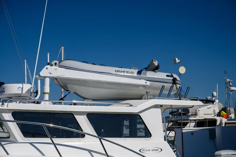 Slide: The Image of 2021 Ocean Sport 26/27 boat with a Highfield dinghy on top, docked under clear blue sky. - 7