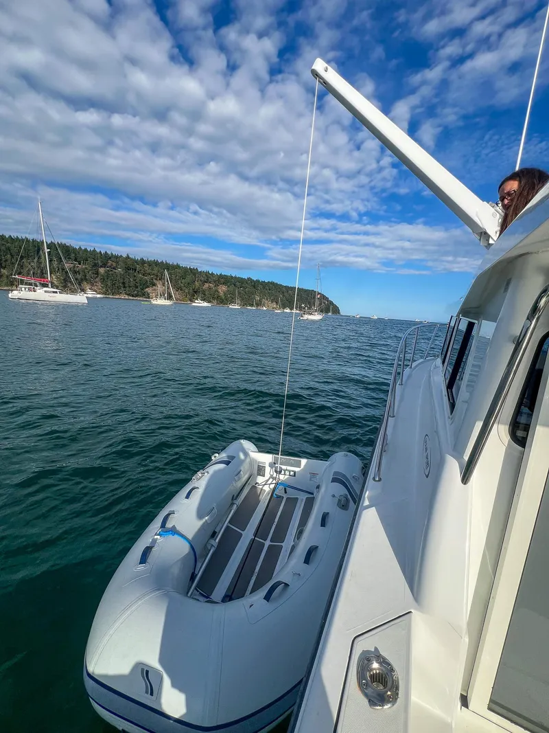 Slide: The Image of Ocean Sport 26/27 boat with dinghy on calm water, 2021 model, scenic coastal view. - 9