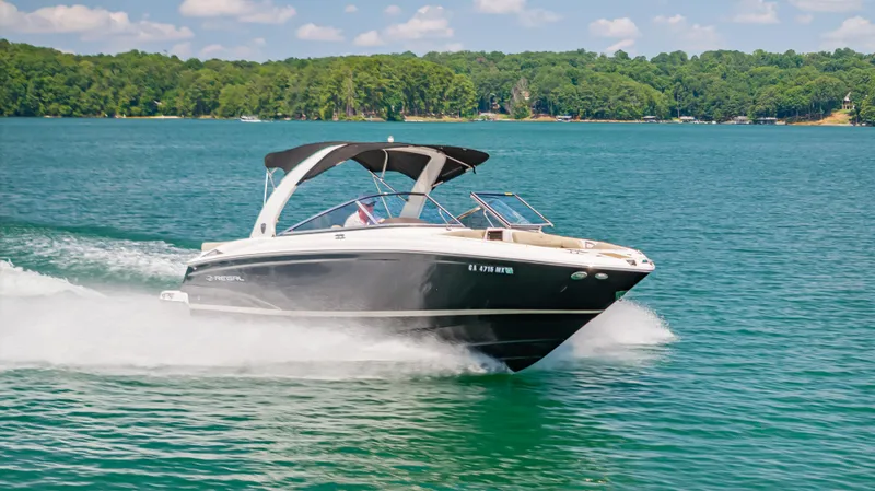 Slide: The Image of 2015 Regal 2700 ES Bowrider cruising on a scenic lake with lush green shoreline. - 3