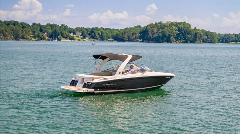 Slide: The Image of 2015 Regal 2700 ES Bowrider on a serene lake with lush green shoreline. - 7