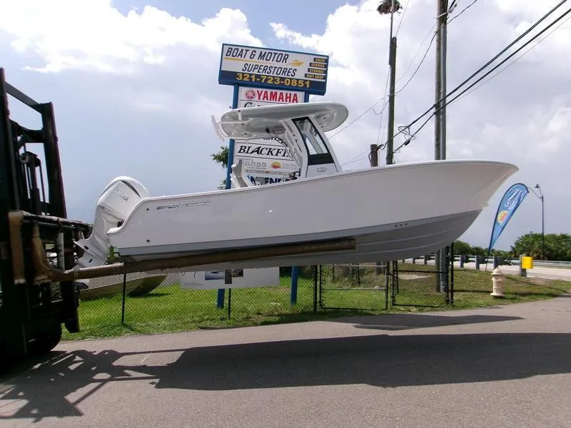 Slide: The Image of 2026 Sportsman Open 232 boat lifted by forklift at dealership, clear sky background. - 5