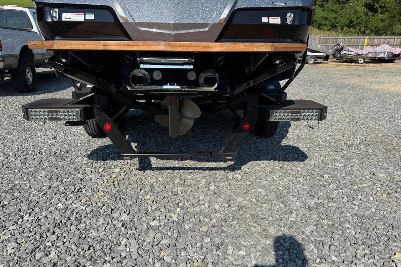 Slide: The Image of Rear view of 2020 MasterCraft X22 boat on gravel, showcasing propeller and platform. - 17