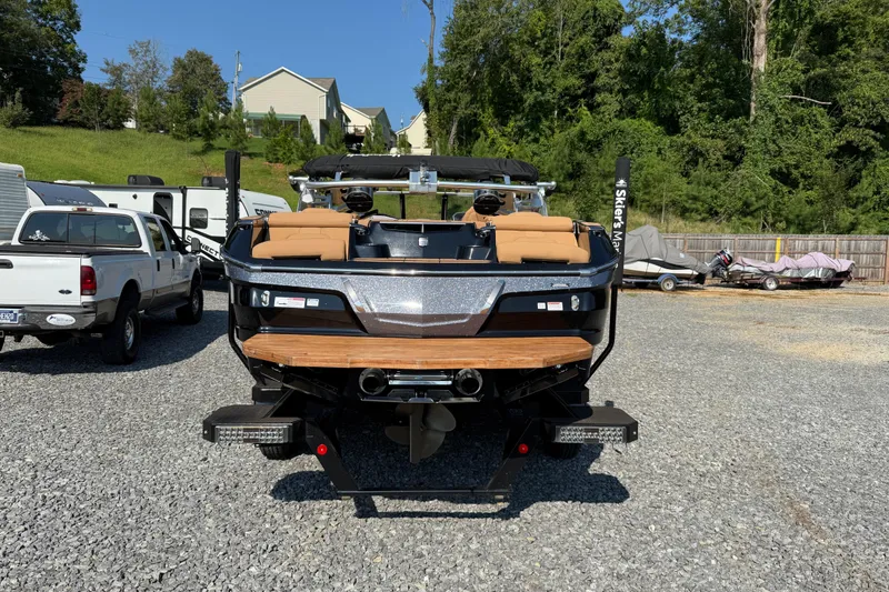 Slide: The Image of 2020 MasterCraft X22 boat in a gravel lot, surrounded by vehicles and trees. - 18