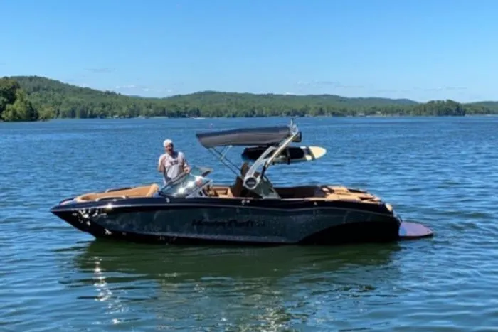 Slide: The Image of 2020 MasterCraft X22 boat on a serene lake with a person onboard. - 4