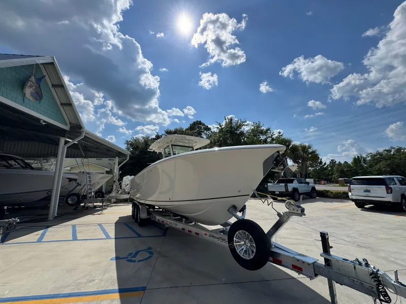 Slide: The Image of 2025 Sailfish 312 CC boat on trailer under sunny sky at dealership. - 10