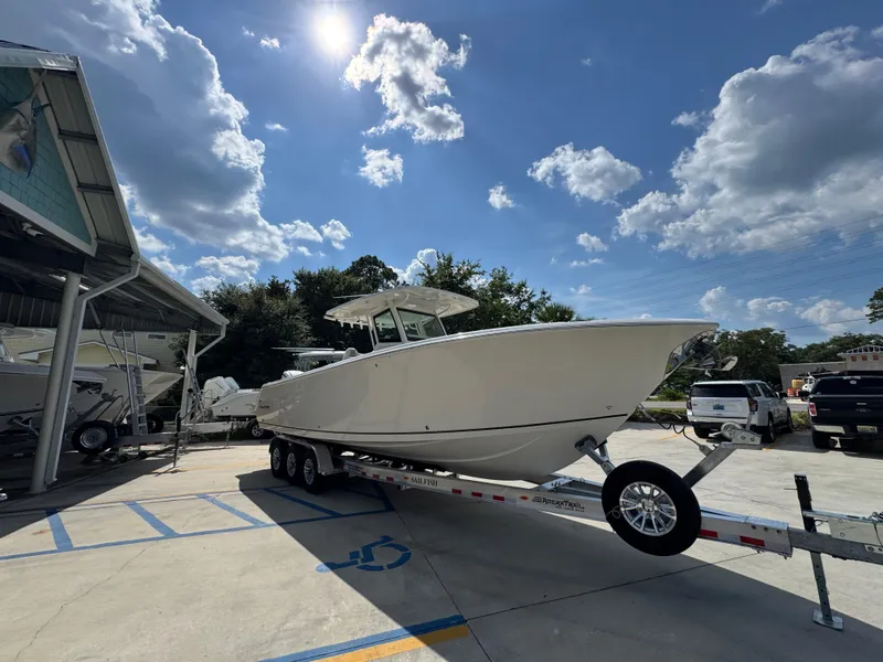 Slide: The Image of 2025 Sailfish 312 CC boat on trailer under sunny sky at dealership. - 11