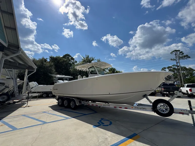 Slide: The Image of 2025 Sailfish 312 CC boat on trailer under sunny sky with clouds. - 12
