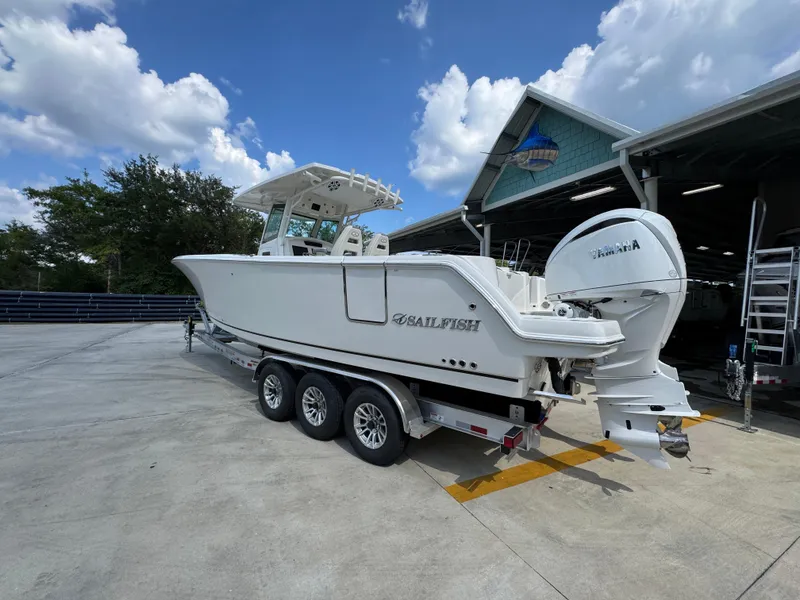 Slide: The Image of 2025 Sailfish 312 CC boat on trailer, parked outdoors under a partly cloudy sky. - 23