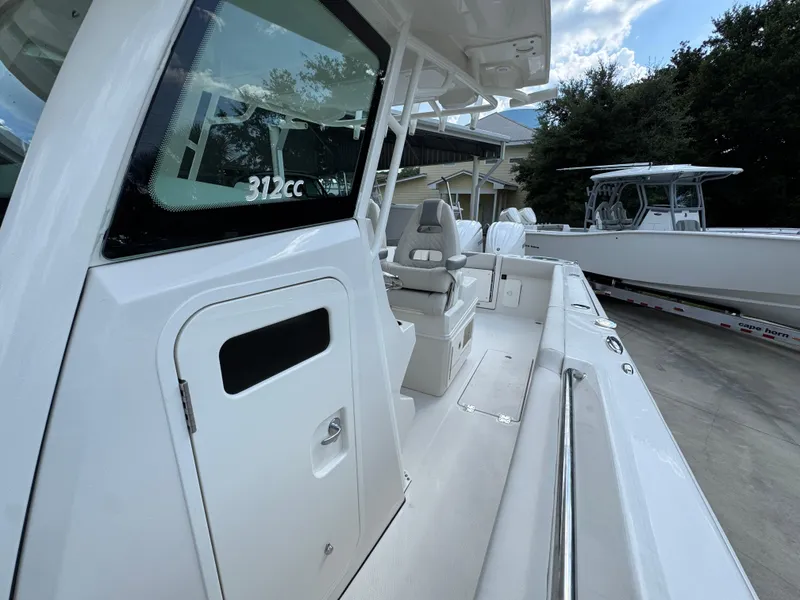 Slide: The Image of 2025 Sailfish 312 CC boat interior with seating and console, docked outdoors. - 31