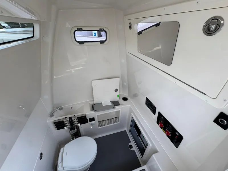 Slide: The Image of Interior of 2025 Sailfish 312 CC boat featuring a compact, modern bathroom with toilet and window. - 34