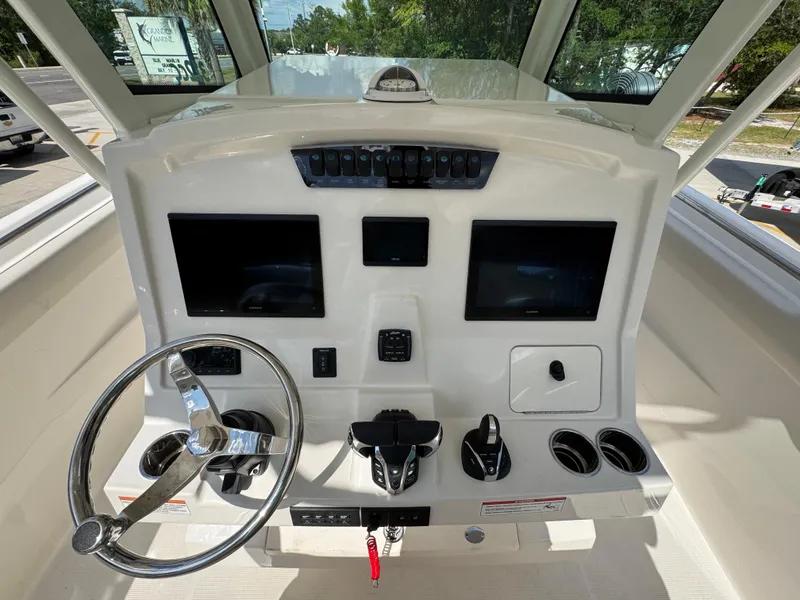 Slide: The Image of 2025 Sailfish 312 CC boat dashboard with steering wheel, dual screens, and control panel. - 38