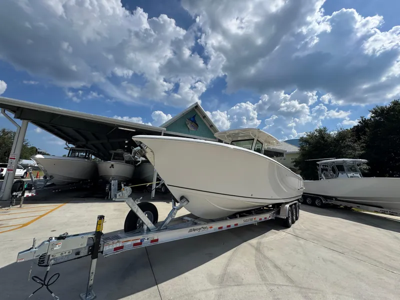 Slide: The Image of 2025 Sailfish 312 CC boat on trailer under cloudy sky at marina. - 5