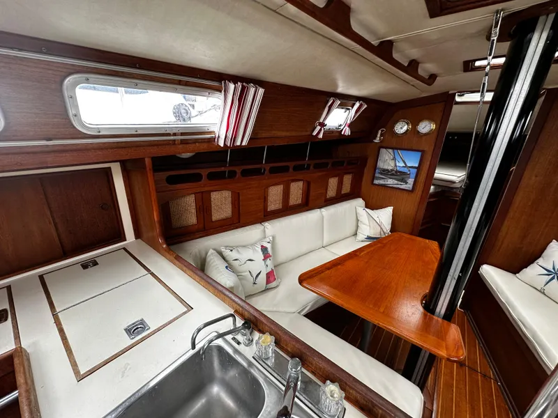 Slide: The Image of Interior of 1987 Ericson 34 2 sailboat with wood finish, white seating, and compact kitchen area. - 10