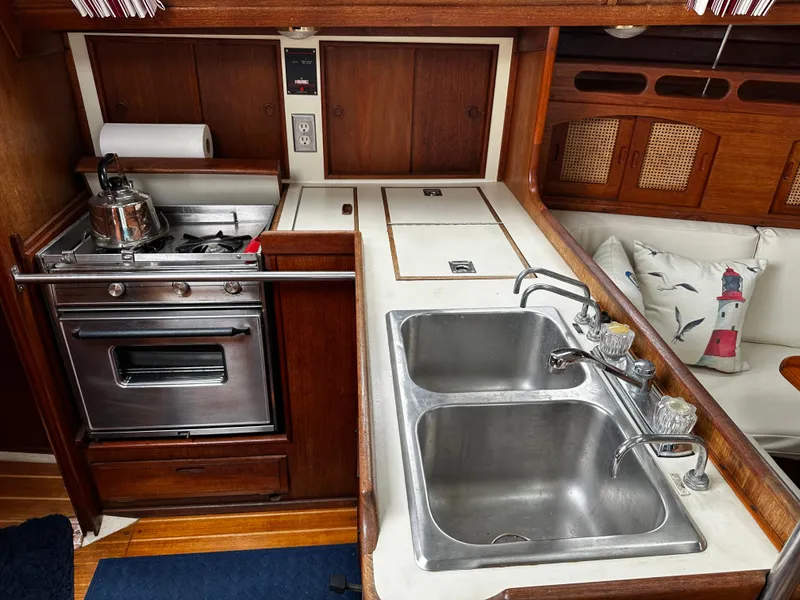 Slide: The Image of 1987 Ericson 34 2 yacht kitchen with stove, double sink, and wooden cabinetry. - 12