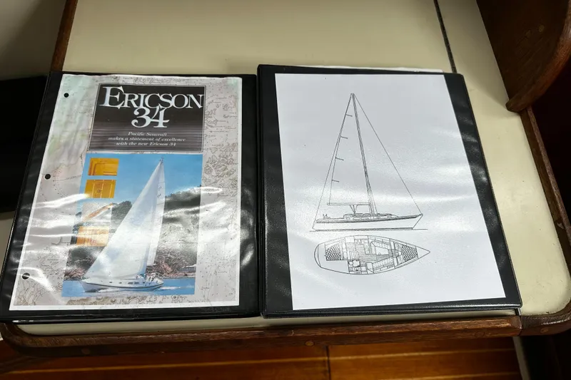 Slide: The Image of Two binders featuring Ericson 34 sailboat brochure and schematic drawing on a table. - 19