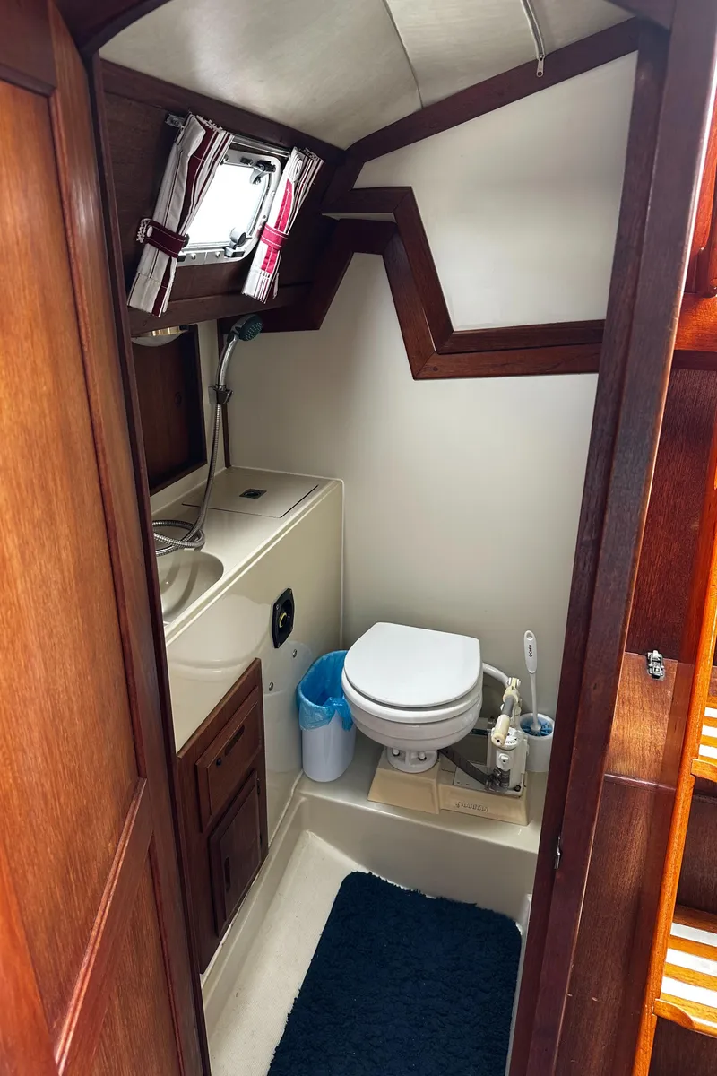 Slide: The Image of 1987 Ericson 34 2 yacht bathroom with sink, toilet, and wooden cabinetry. - 23