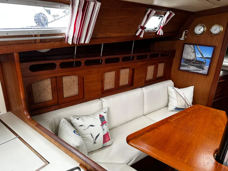 Slide: The Image of Cozy interior of 1987 Ericson 34 2 sailboat with wooden table and white seating. - 9