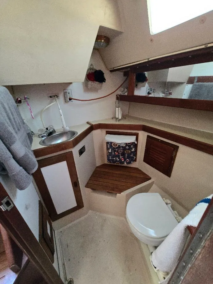 Slide: The Image of 1986 Catalina C-34 boat bathroom with sink, toilet, and wooden accents. - 38