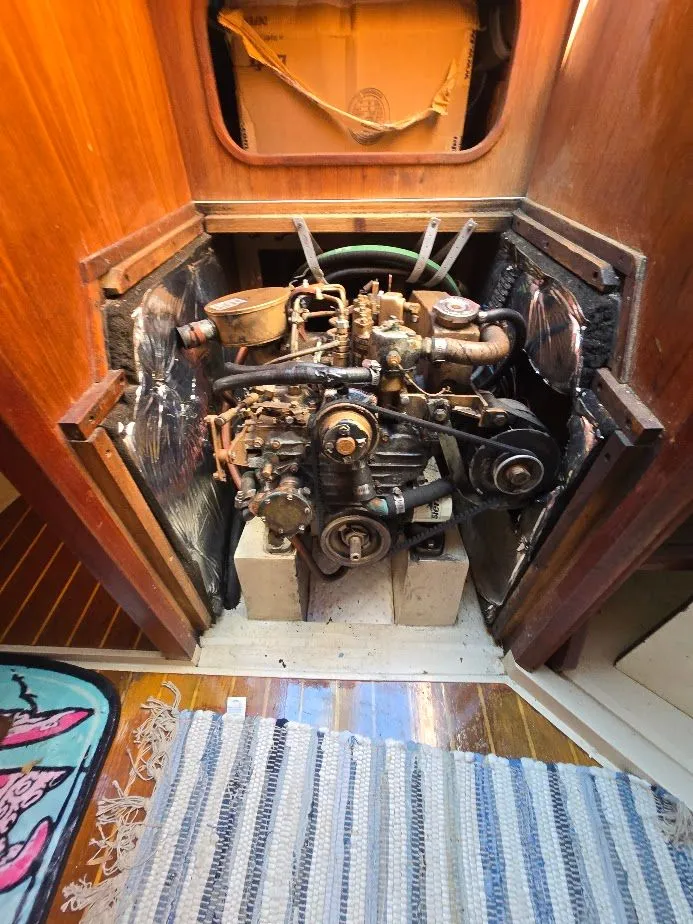 Slide: The Image of 1986 Catalina C-34 engine compartment with exposed mechanical components and surrounding wooden panels. - 39