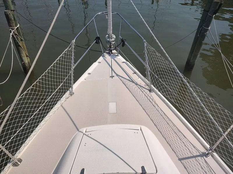 Slide: The Image of Bow of 1986 Catalina C-34 sailboat docked, featuring safety netting and calm water. - 6