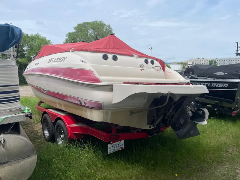 Slide: The Image of 2003 Larson 214 boat with red cover on trailer, parked on grass. - 2