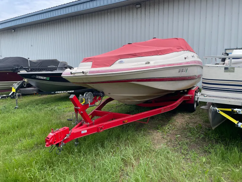 Slide: The Image of 2003 Larson 214 boat with red cover on a red trailer, parked outdoors. - 3