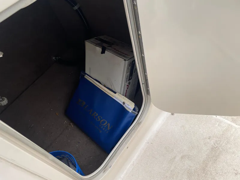 Slide: The Image of Storage compartment of a 2003 Larson 214 boat with a blue Larson bag and a box. - 6