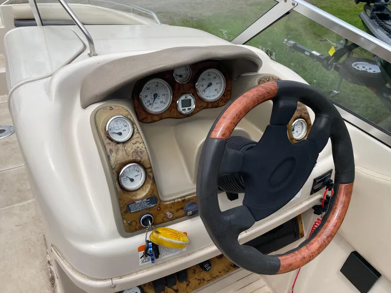 Slide: The Image of Steering wheel and dashboard of a 2003 Larson 214 boat, featuring gauges and controls. - 8