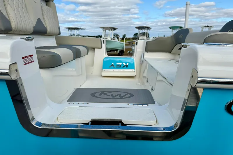 Slide: The Image of 2025 Key West 291 FS boat interior with seating and logo, under a partly cloudy sky. - 13