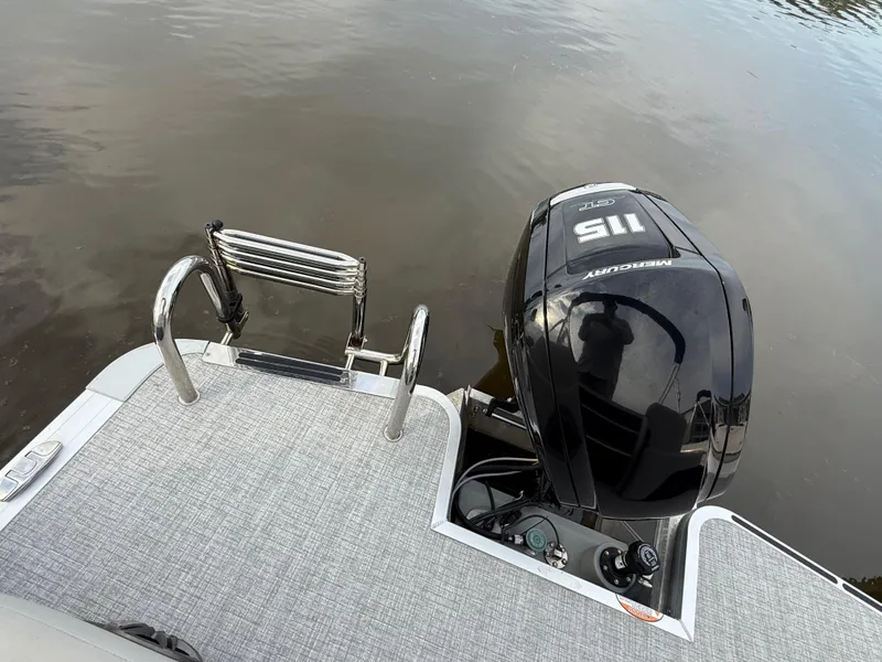 Slide: The Image of 2024 Harris Cruiser 230 boat with Mercury 115 outboard motor and swim ladder on calm water. - 11