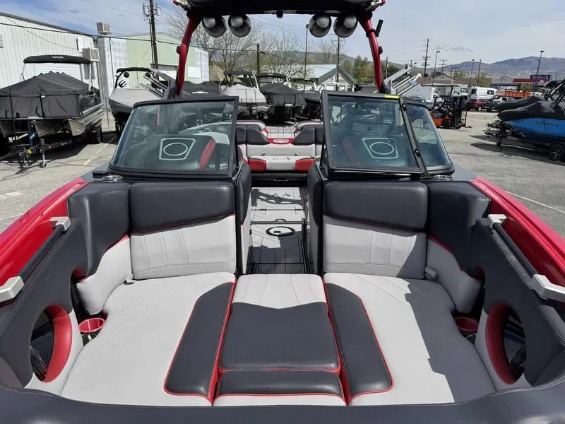 Slide: The Image of 2019 Supra SE550 boat interior with red and gray seating, open windshield, and outdoor setting. - 13
