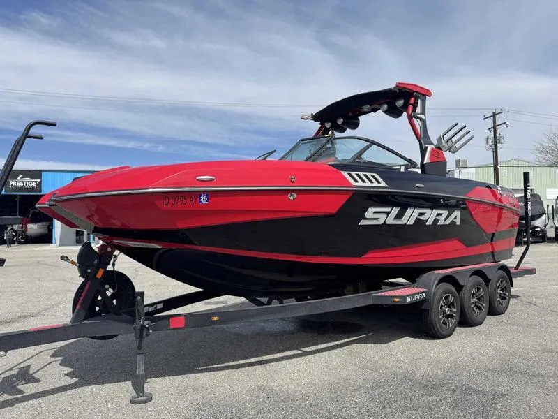Slide: The Image of 2019 Supra SE550 boat in red and black on a trailer, parked outdoors. - 3
