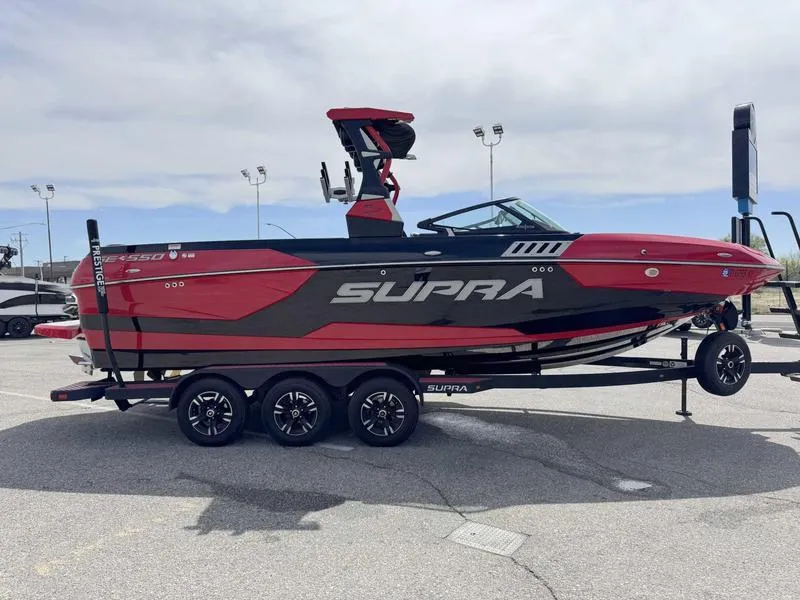 Slide: The Image of 2019 Supra SE550 boat in red and black on a trailer, parked outdoors. - 4