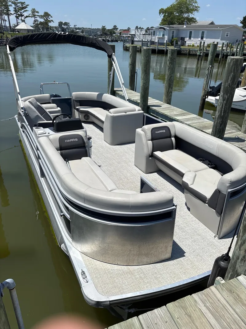 Slide: The Image of 2024 Harris Cruiser 230 pontoon boat docked, featuring spacious seating and sleek design. - 0